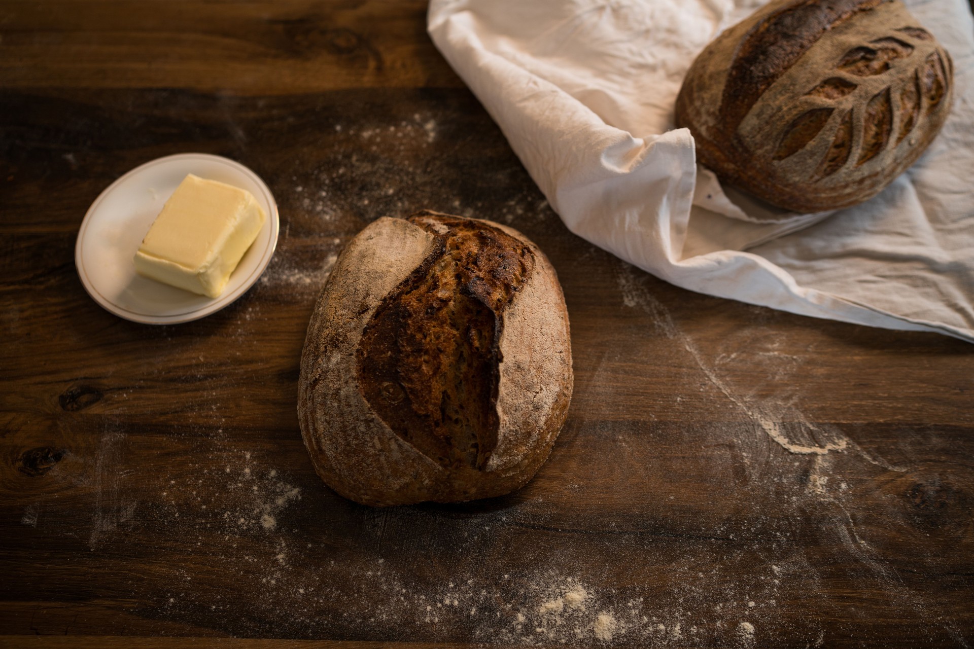 Freshly baked sourdough bread loaves with butter on rustic wooden table